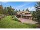 Expansive lawn with mature trees frames this house with an attached garage and stone-and-wood accents at 1456 Shavano Ct, Evergreen, CO 80439