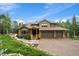 Exterior view of house features mature trees, stone pathway, and an attached two-car garage at 1456 Shavano Ct, Evergreen, CO 80439