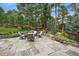 Stone patio featuring an outdoor seating area with views of the landscaped backyard and surrounding trees at 1456 Shavano Ct, Evergreen, CO 80439