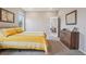 Neutral bedroom with a yellow striped bedspread, wood dresser, and view to the dining area at 5928 N Odessa St, Aurora, CO 80019