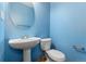 Bright powder room features blue walls, a pedestal sink, and a toilet at 2960 Inca St # 308, Denver, CO 80202