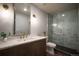 A modern bathroom featuring a marble tiled shower, glass door, stylish sink, and vanity at 9007 E 60Th Ave, Denver, CO 80238