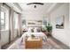 Airy main bedroom offers a tray ceiling, neutral tones, bedside tables, and a cozy sitting area at 9007 E 60Th Ave, Denver, CO 80238
