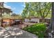 A serene backyard featuring mature trees, a deck with a grill, a brick patio, and a detached garage at 1226 Clayton St, Denver, CO 80206