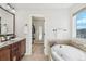 Bright bathroom with soaking tub, wood cabinets, and a doorway to a walk-in closet at 5077 W 108Th Cir, Westminster, CO 80031
