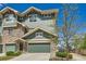 Townhouse exterior with green siding, stone accents, and a two-car garage, set in a beautifully landscaped community at 4795 E 98Th Pl, Thornton, CO 80229