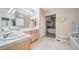 Bright bathroom featuring a double vanity, soaking tub, and organized walk-in closet at 12136 Desert Hills St, Parker, CO 80138