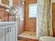 Bathroom featuring tiled walls, a vanity, a shower, and a window for natural light at 675 S Quivas St, Denver, CO 80223