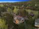 Expansive aerial view of a two-story home in a lush, wooded landscape with rolling hills at 31402 N Bermuda Dunes Dr, Evergreen, CO 80439