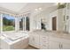 Bright primary bathroom featuring a soaking tub with a view, dual sinks, and great natural light at 31402 N Bermuda Dunes Dr, Evergreen, CO 80439