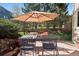 Outdoor patio with dining set, umbrella for shade, and views of a lush, green landscaped backyard at 31402 N Bermuda Dunes Dr, Evergreen, CO 80439