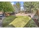 A spacious, landscaped backyard featuring a lush lawn, tiered retaining wall, and mature trees at 10908 Oakshire Ave, Highlands Ranch, CO 80126