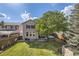 A well-manicured backyard featuring a lush green lawn, a large tree, patio seating, and a hot tub at 10908 Oakshire Ave, Highlands Ranch, CO 80126