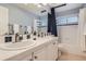 Well-lit bathroom featuring double sinks, a shower-tub combo, and classic white tiling with blue accents at 10908 Oakshire Ave, Highlands Ranch, CO 80126