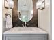Close up of a bathroom vanity with wood grain accents, a white countertop, and an oval mirror at 31756 Buffalo Park Rd, Evergreen, CO 80439