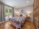 Bright bedroom with wood floors, a colorful quilt, and outdoor views through a large window at 31756 Buffalo Park Rd, Evergreen, CO 80439