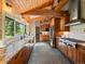 Charming kitchen with wood cabinets, granite counters, stainless steel appliances, wood ceiling beams, and large windows at 31756 Buffalo Park Rd, Evergreen, CO 80439