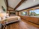 This main bedroom features a stone fireplace, wood beams, and large windows with views of the golf course at 31756 Buffalo Park Rd, Evergreen, CO 80439