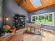 A bright home office with vaulted wood ceilings, built-in shelving, and a large window overlooking a landscaped yard at 31756 Buffalo Park Rd, Evergreen, CO 80439