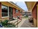Covered backyard porch with a step-up to the yard and an entrance to the home, surrounded by greenery at 345 Central Ave, Brighton, CO 80601