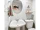 A pedestal sink with a round mirror and a small picture on the wall at 7131 Raritan St, Denver, CO 80221