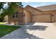 Tan home featuring a two-car garage, brick accents, and well-maintained landscaping at 16141 W 64Th Way, Arvada, CO 80007