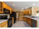 Oak kitchen with tile flooring and black appliances including refrigerator, stove, and microwave at 16141 W 64Th Way, Arvada, CO 80007