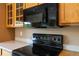 This kitchen features a black electric range beneath a mounted microwave and oak cabinets at 16141 W 64Th Way, Arvada, CO 80007