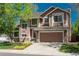 Charming two-story home featuring a stone-accented facade, two-car garage, and a well-maintained front yard with mature trees at 19099 E Creekside Dr, Parker, CO 80134