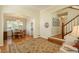 Open-concept living room with hardwood floors and large area rug leading to the dining room and staircase at 19099 E Creekside Dr, Parker, CO 80134