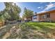 Exterior view of a charming brick home with a well-maintained lawn, wooden fence, and outdoor seating area at 17675 E Girard Ave, Aurora, CO 80013