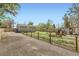 Charming backyard featuring a garden, shed, and a rustic fence bordering the gravel driveway at 7101 E 66Th Ave, Commerce City, CO 80022