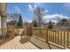 Wooden deck overlooking a spacious fenced backyard with a combination of lawn and mature trees at 6790 W Crestline Ave, Littleton, CO 80123