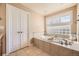 Large soaking tub with tile surround and shuttered window for natural light at 6790 W Crestline Ave, Littleton, CO 80123