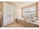 Bright bathroom featuring a large soaking tub, white cabinets, and plenty of natural light at 6790 W Crestline Ave, Littleton, CO 80123