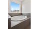 A soaking tub is surrounded by light grey tiling in the main bathroom at 9248 Salida St, Commerce City, CO 80022