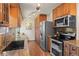 Galley kitchen featuring stainless steel appliances, warm wood cabinetry, and granite countertops for a modern, sleek design at 4323 W Ponds Cir, Littleton, CO 80123