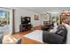 Open-concept living room with hardwood floors, a comfortable black leather sofa, and seamless access to the kitchen at 4323 W Ponds Cir, Littleton, CO 80123