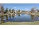Scenic view of a tranquil pond reflecting houses and trees with clear blue sky above at 4323 W Ponds Cir, Littleton, CO 80123