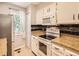 Bright kitchen with white cabinets, granite counters, and modern appliances, window, and pantry at 9736 W Cornell Pl, Lakewood, CO 80227