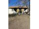 Damaged home with boarded windows and debris in the yard at 1165 S Winona Ct, Denver, CO 80219