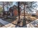 Brick two-story home with mature trees, front yard, a sidewalk and a nearby car at 1525 S Holly St # 105, Denver, CO 80222