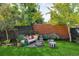 Well-manicured backyard featuring a cozy lounge area, lush lawn, privacy fence, and mature trees at 2383 Jasmine St, Denver, CO 80207