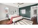 Cozy bedroom features hardwood floors, a ceiling fan, a stylish rug, and a green accent wall at 2383 Jasmine St, Denver, CO 80207