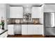 Bright kitchen with stainless steel refrigerator, light gray backsplash, and modern white cabinets at 2383 Jasmine St, Denver, CO 80207