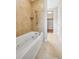 Bathroom featuring a white soaking tub with tile surround and access to a walk-in closet at 3482 E 28Th Ave, Denver, CO 80205