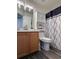 Well-maintained bathroom featuring wood vanity, framed mirror, and decorative shower curtain at 5898 W Asbury Pl, Lakewood, CO 80227