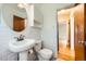 A compact, tiled bathroom with a pedestal sink, toilet, and view into another room at 2565 S Gaylord St, Denver, CO 80210