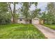 Inviting home showcasing a green lawn, mature trees, and attached garage for convenient parking at 2565 S Gaylord St, Denver, CO 80210