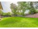 Expansive backyard with green lawn, mature trees, brick retaining wall and a shed at 8866 E Easter Ave, Centennial, CO 80112